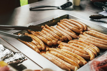 Grilling sausages on barbecue grill in the garden. Chicken sausages. Public BBQ place in Australia. Picnic in park.