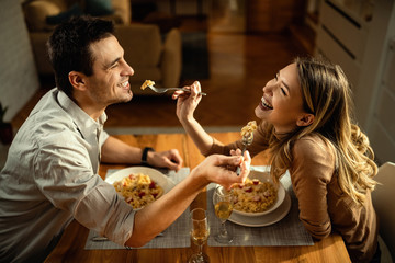 Happy couple in love sharing food at dining table.