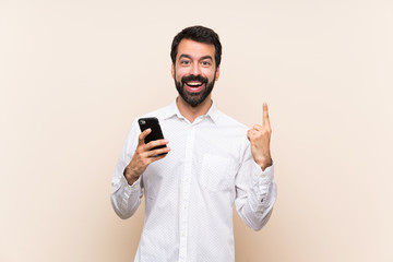 Young man with beard holding a mobile pointing up a great idea