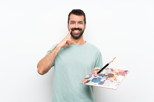 Young artist man holding a palette over isolated background smiling with a happy and pleasant expression