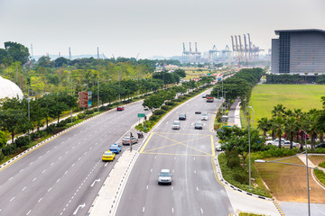 SINGAPORE - MARCH 23, 2013: Cars traffic on Sheares ave with Singapore cargo port on background. Currently it is the world's second-busiest port in terms of total shipping tonnage.