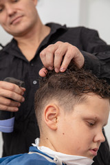 Obraz premium The hairdresser is watering the hair of a boy in the salon