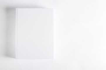 Mockup of closed blank square book at white textured paper background