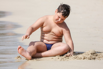 A boy plays in the sand on the seashore © schankz