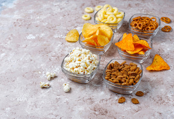 Salty snacks. Pretzels, chips, crackers,popcorn in bowls. Unhealthy products. food bad for figure, skin, heart and teeth. Assortment of fast carbohydrates food