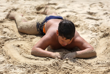 A boy plays in the sand on the seashore