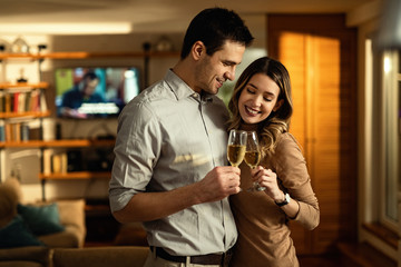Young happy couple toasting with Champagne at home.