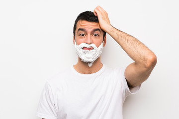 Man shaving his beard over isolated white background with an expression of frustration and not understanding