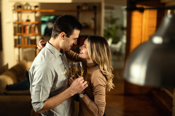 Happy couple in love talking while drinking Champagne at home.
