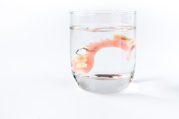 denture is cleaned in a glass of water. proper hygiene.