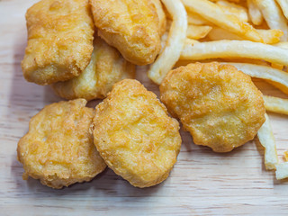 Top view or directly above of closeup crispy nuggets and french fried on wooden table.