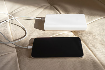 White colored power bank charging black color smart phone.