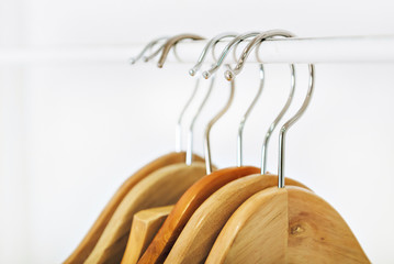 a few empty hangers on a white bracket against a white wall . lack of clothing