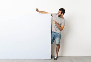 Young handsome man with beard holding a big blue empty placard making a selfie