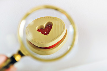 a red heart in a wooden round box is held by a man's hand