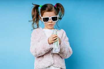 portrait of glamorous little caucasian kid girl in sunglasses isolated over blue background. cool...