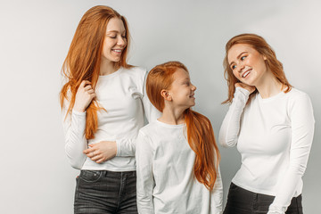 portrait of gorgeous positive caucasian sisters with unusual red hair colour, redhaired girls posing at camera, look at each other and laugh, smile. natural ginger hair, red hair, auburn