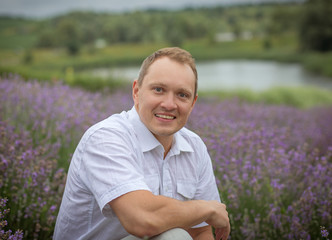 Naklejka na ściany i meble young man in a white shirt in a lavender field in summer enjoying his holidays