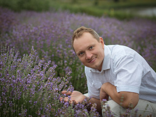  young man in a white shirt in a lavender field in summer enjoying his holidays