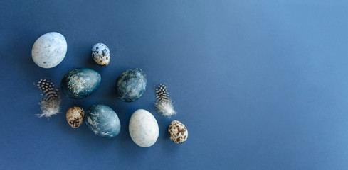 Fototapeta na wymiar Beautiful group ombre blue Easter eggs with quail eggs and feathers on a blue background. Easter concept. Border eggs. Copy space for text.