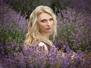  blonde girl in lavender field in summer enjoying vacation