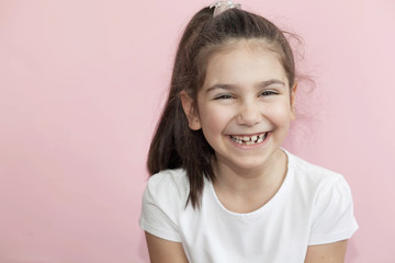 Portrait of happy laughing child girl on pastel background. Smiling kid. Positive emotions.