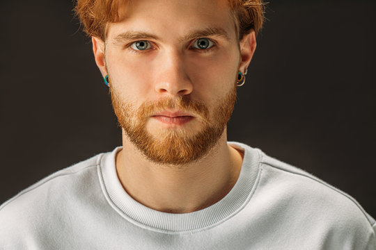 portrait of seriously looking caucasian man with red hair and beard isolated over black background. confident male in white casual shirt look at camera wih piercing gaze, posing at camera