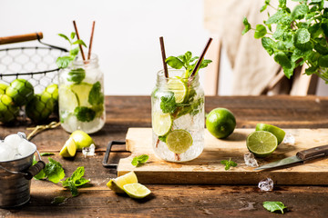 Refreshing mojito drink in glass jar with paper straws. Wooden table. White background 