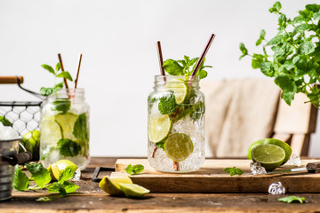 Refreshing mojito drink in glass jar with paper straws. Wooden table. White background 