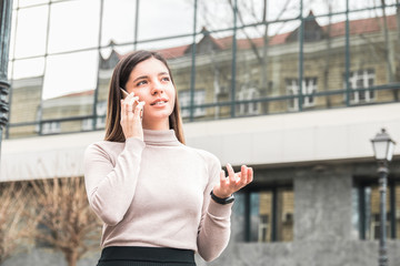 Fototapeta premium young attractive and confident businesswoman speaking on the phone in front of business centre