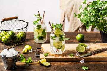 Refreshing mojito drink in glass jar with paper straws. Wooden table. White background 