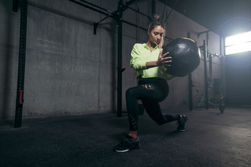 Young woman exercising with medicine ball in gym.