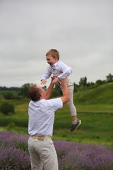  happy father rises to the sky  little son up, having fun and relaxing in a lavender field in summer