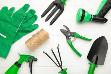 Gardening tools on white wooden background, top view