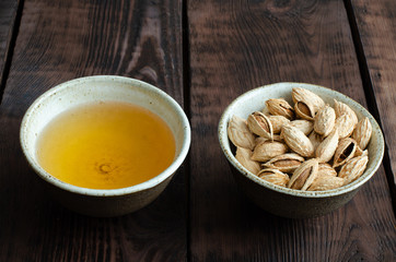 Almonds in nutshell and tea in cup on wooden background