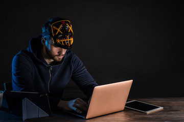 professional hacker male use laptop to gain unauthorized access to data, dark space. person in...
