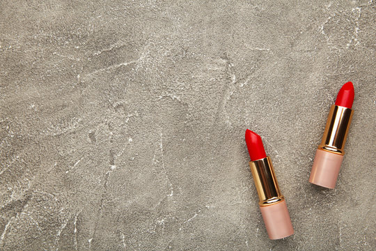 Two red lipsticks on the grey table, top view