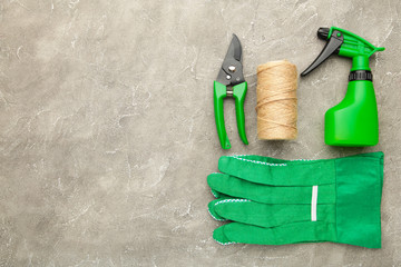 Gardening tools on grey concrete background, top view