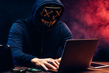 cyber criminal hacking into a computer. anonymous male stealing money from bank account, typing...