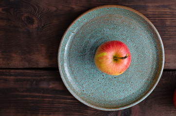 Organic apple on earthen dish on wooden background