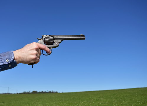 Man holding a .44 or .45 caliber revolver outdoors with blue sky.