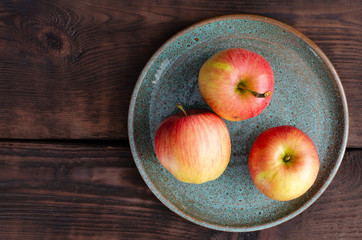 Organic apples on earthen dish on wooden background
