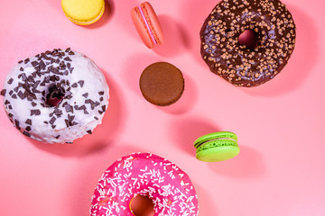 Fresh glazed donuts and french macaroons isolated on a pink background