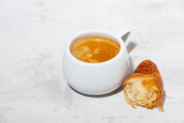 cup of espresso and fresh croissants on white background