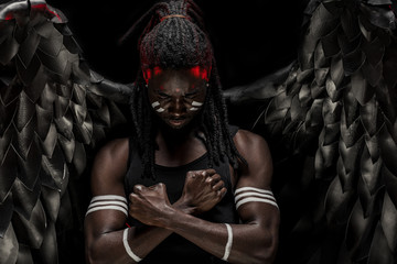 strong black angel with cool wings, stand posing at camera. man fall from heaven, angel with muscular body gained freedom. angel restraining himself not to do bad to people. fantasy concept