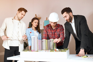 Confident talented engineers working together in a architect studio.standing behind the table with a model. close up photo