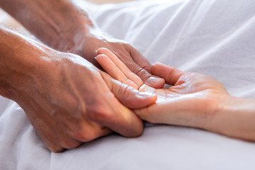 Close-up view of masseur giving relaxing hand massage to a client. Hand massage to a woman in a cosy home environment. Massage and body care - obrazy, fototapety, plakaty
