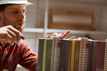 talented architect wearing protective helmet is keen on measuring process. close up photo, guy...