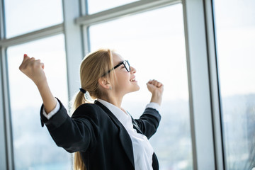 Business woman excited hold hands up raised arms celebrate victory in modern office
