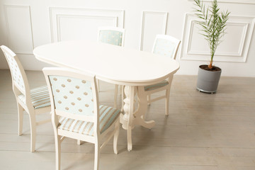 White tables and chairs for dinner in a classic interior. Upholstered chairs for comfortable sitting at the table